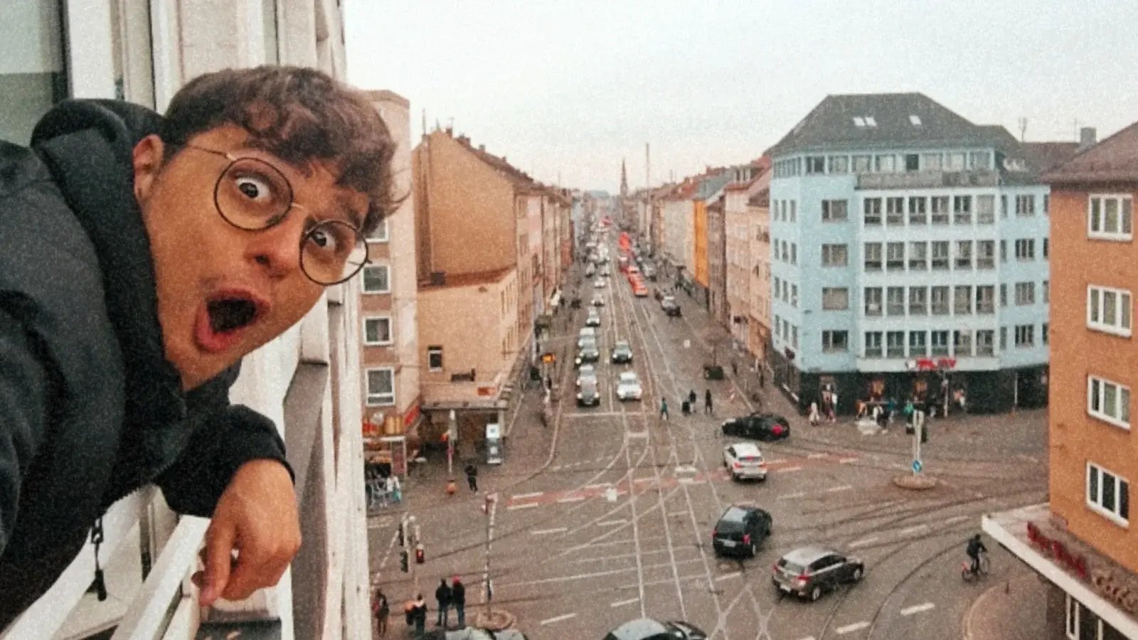 guy looking out an apartment window in the city