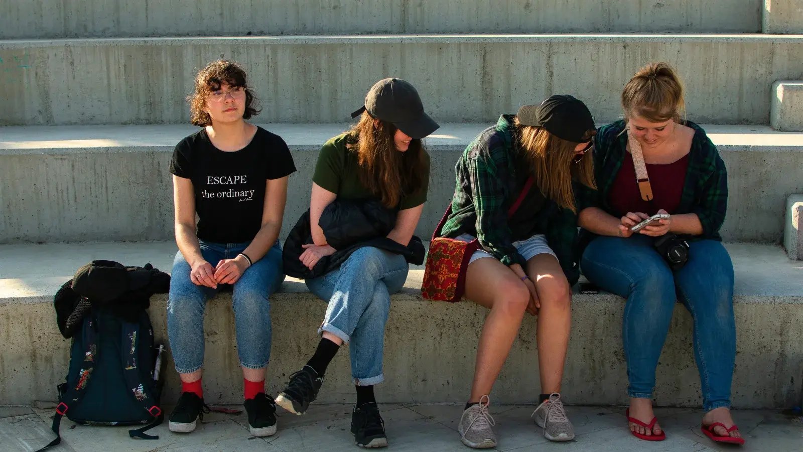 4 DTS students sitting on a bench, 3 are looking at a picture on one girl's phone