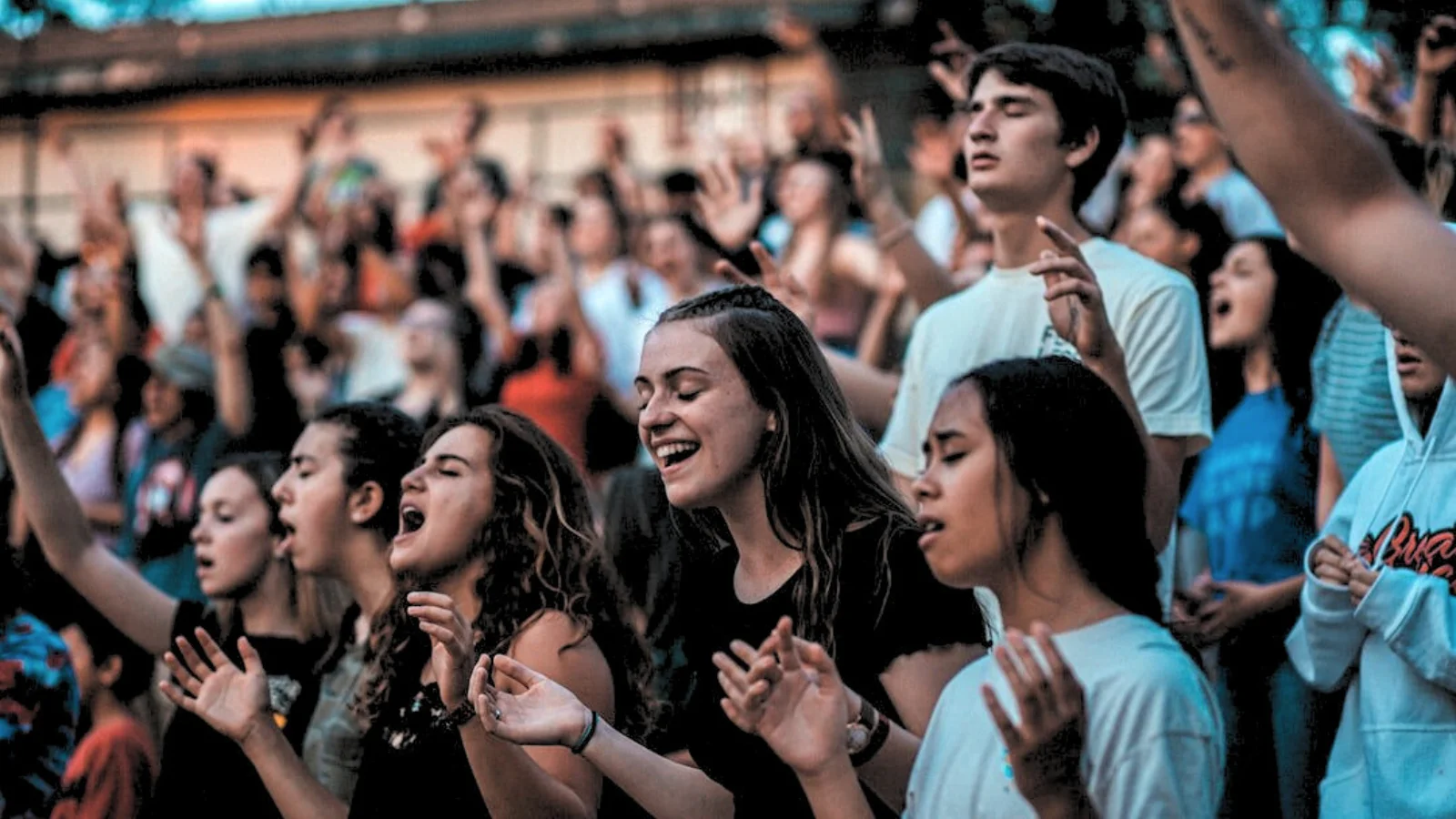 a crowd of young people singing in worship